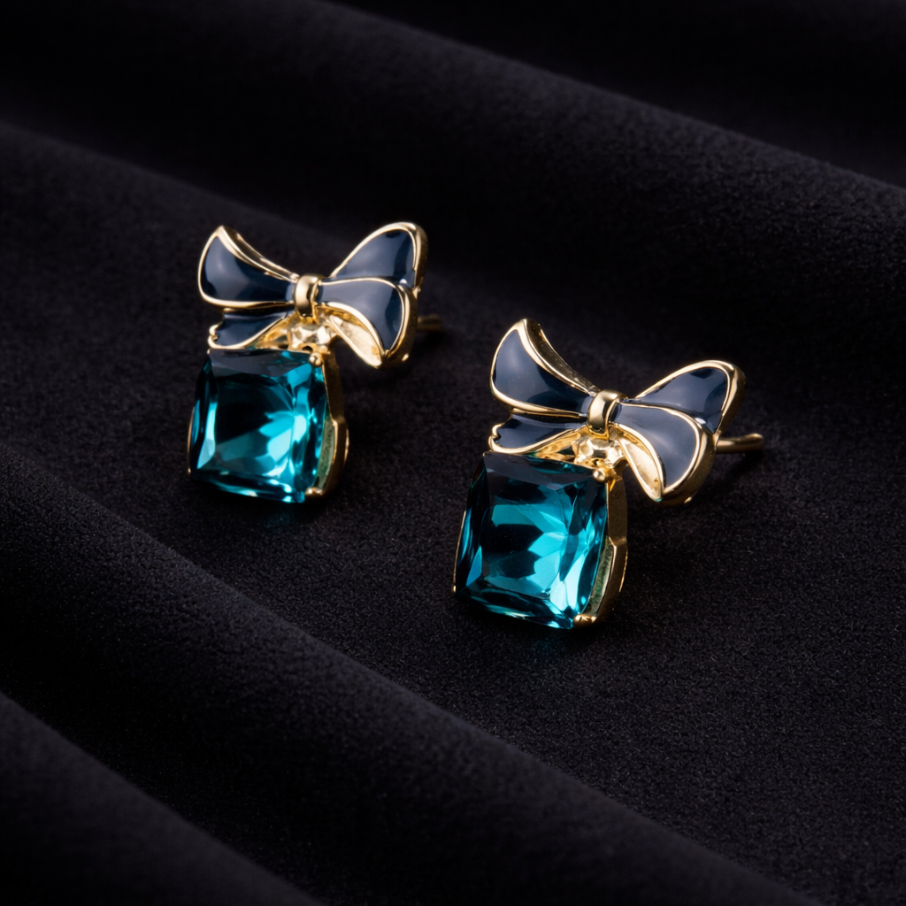 Pair of earrings with blue gemstones and gold bows on a black background