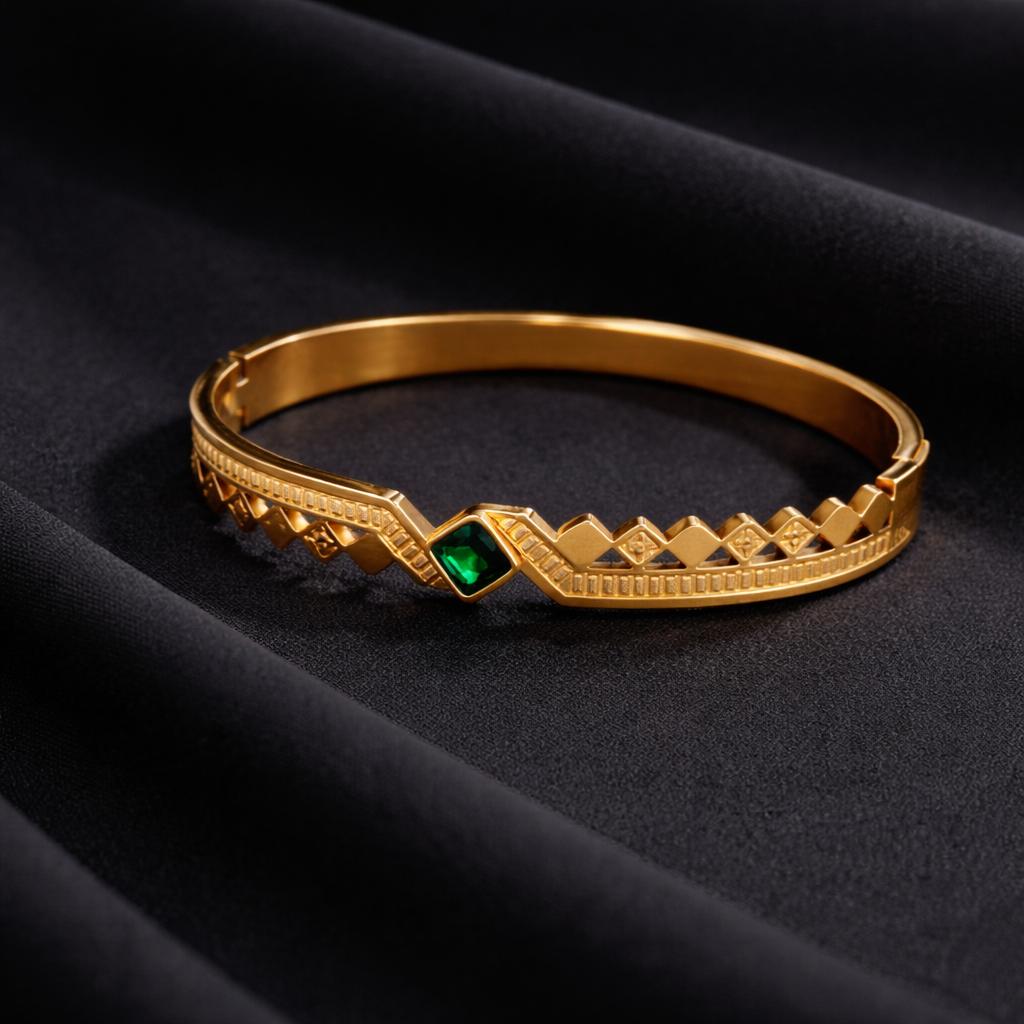Gold bracelet with a green gemstone on a black fabric background