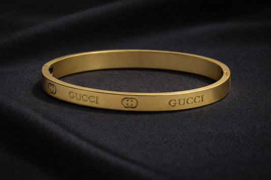Gold Gucci bracelet on a dark fabric background